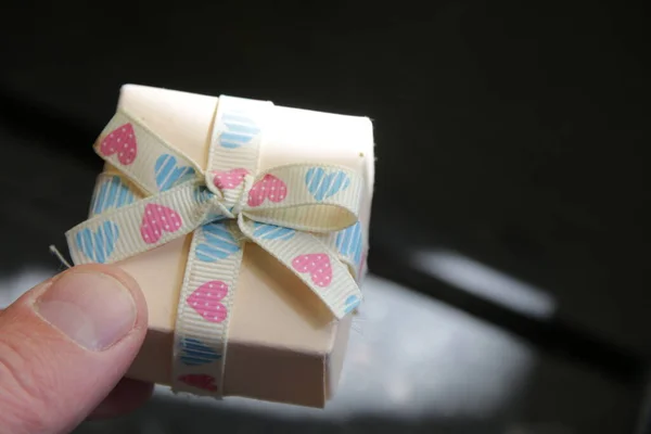 A mans hand holds a gift box with a ribbon. — ストック写真