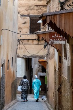 Fas 'taki Fez Medina' da. Geleneksel kıyafetler giymiş iki peçeli kadın dar bir sokakta yürüyor..
