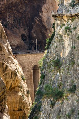 Caminito del Rey 'de. Demiryolu hattı Gaitanes geçitlerinin dar ve dikey kanyonunun diğer tarafında bir tünel ve bir viyadük geçidini geçer.