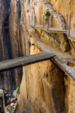 Caminito del Rey 'de. Yürüyüşçüler ve turistler Gaitanes geçitlerinin eski patikalarına bakan yaya köprüsünde dururlar.