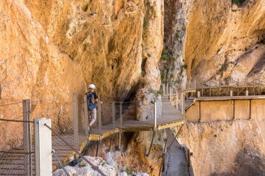 Caminito del Rey 'de. Yürüyüşçüler, Guadalhorce nehrinin dikey ve dar kanyonuna bakan yaya köprüsünde yürürler.