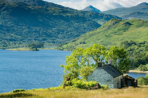 沿着苏格兰的西高地大道 Loch Lomond的照片 画面中隐藏在一些树木和灌木丛后面的一座古老的白色小房子 — 图库照片