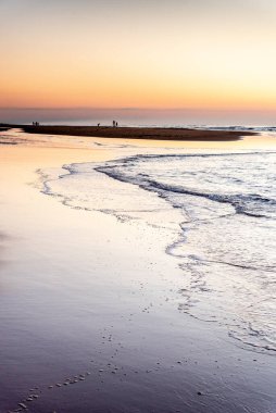 Aylak grupları, Fransa 'daki Cap Ferret' te Atlantik Okyanusu 'ndaki bir sahilde gün batımında göze çarpan siluetler yaratırlar.
