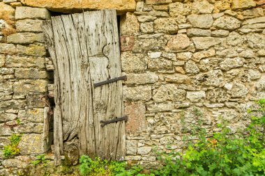 Saint Guilhem le Desert 'e hac yolunda. Lozere, Fransa 'da bir çiftliğin taş duvarına eski ahşap bir kapı.