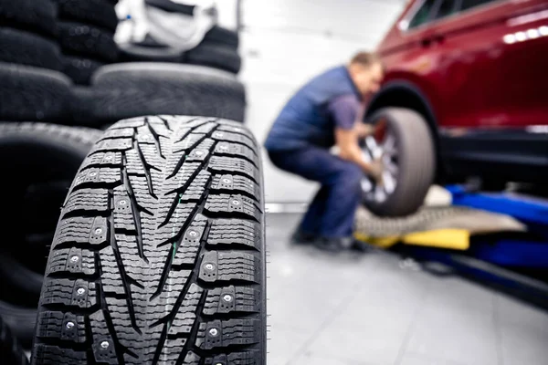 Koncepce autoservis výměna zimních a letních pneumatik. Mechanik drží kola v garáži — Stock fotografie