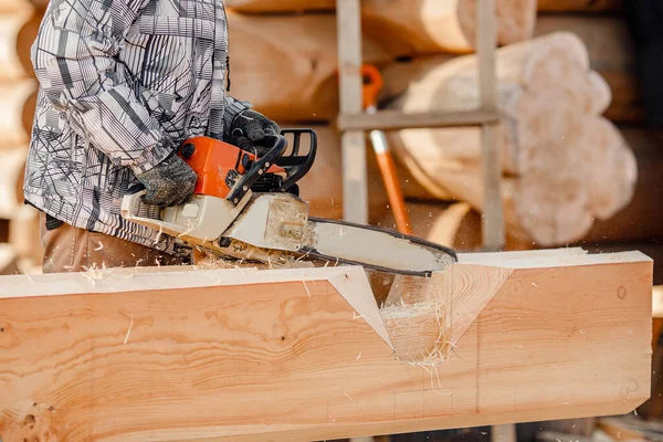 Aserrado de carpintero de trabajo industrial con tronco de motosierra, sitio de construcción de marco de construcción de casa de madera — Foto de Stock