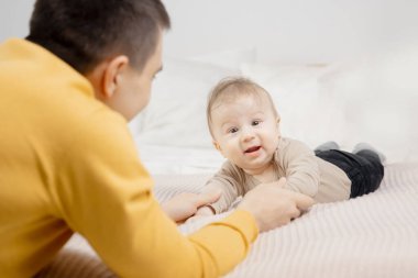 Baba, küçük oğluyla yatak odasında oynuyor.