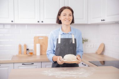 Hafif İskandinav mutfağının arka planında kadının elinde ev yapımı ekmek ve pizza yapmak için nefis havadar hamur.