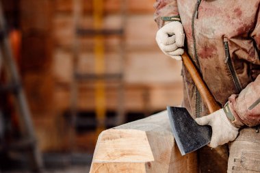 Baltayla çalışan marangoz kütükle çalışıyor. Ahşap işi, ev iskeleti.