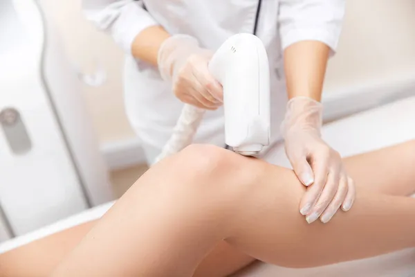 Mestre remove cabelo com laser de pernas de mulher bonita, saúde e spa de cuidados de beleza — Fotografia de Stock