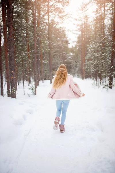 Boldog fiatal szőke nő szemüvegben, rózsaszín kabát téli ruhák futnak havas erdő naplemente — Stock Fotó