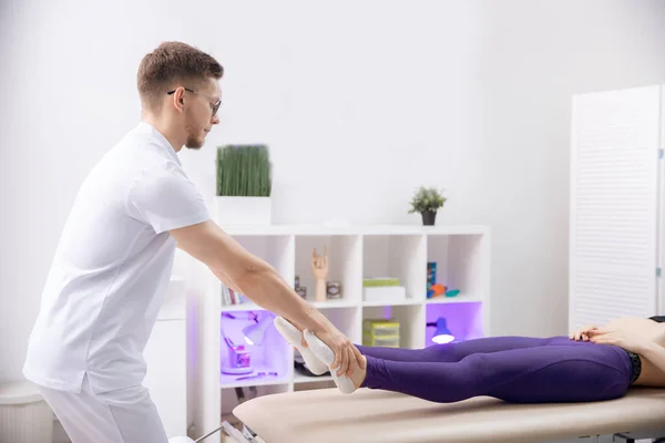 Врач остеопат использует мышечную терапию спортивный массаж для ног спортсменки после тренировки — стоковое фото
