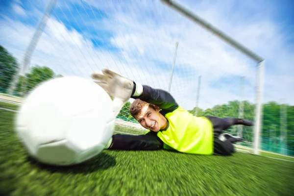 Goalkeeper soccer man catching ball in stadium, action moment of sport