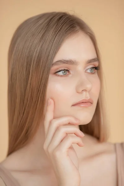 Retrato vertical de una hermosa joven rubia con la piel limpia, fondo beige. Cuidado de belleza cara concepto de moda — Foto de Stock