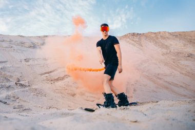 Çölde, snowboard 'un üzerinde aşırı alçalan kum. Kum tepelerinde erkek snowboardcu