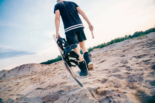 스노보더는 스노보드를 타기 위해 모래 언덕 꼭대기로 올라간다 — 스톡 사진