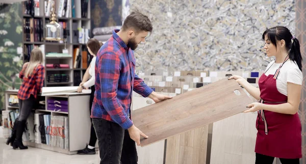 市場でラミネート,男性労働者は家の中で寄木細工の床を選択します,材料の利点についてのコンサルタントの話 — ストック写真