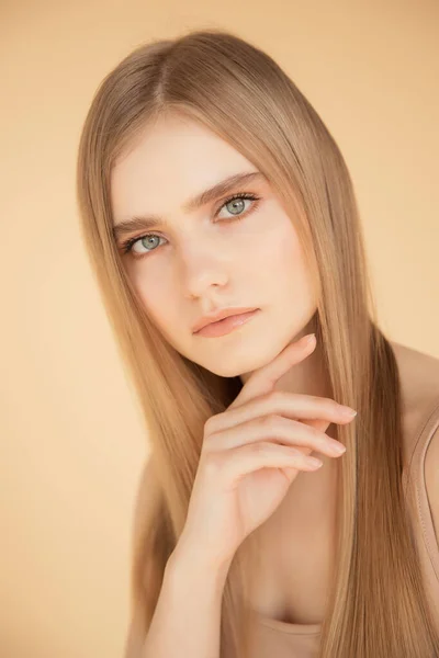 Retrato vertical de una hermosa joven rubia con la piel limpia, fondo beige. Cuidado de belleza cara concepto de moda —  Fotos de Stock