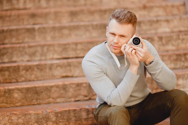 Мужчина путешественник фотограф с небольшой камерой в руках, удивленная компактность и легкость устройства — стоковое фото