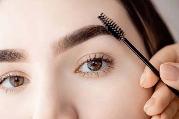 Master tweezers menajiskan rambut alis pada wanita, koreksi alis dengan sisir — Stok Foto