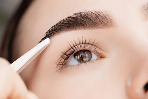 Master tweezers depilation of eyebrow hair in women, brow correction — Stock Photo, Image