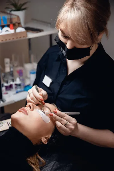 Master pincet nep zwarte lange wimpers mooie vrouwelijke ogen. Wimperverlengingsprocedure — Stockfoto