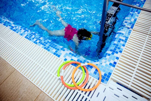 Kid little girl learning to underwater swim pool with ring with coach woman — Stock Photo, Image