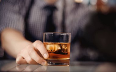 Barman erkek ziyaretçiye buzlu bir bardak viski tutuyor. Konsept dinlenme barda