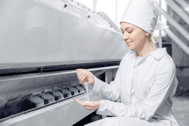 Kadın operatör bitmiş gıda ürünlerinin kalitesini kontrol ediyor. Buğday unu üretmek için modern elektrik değirmeni makineleri
