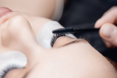 Kirpik uzatma prosedürü kadınlar için mikro patinaj, sonra güzellik salonunda kirpiklerini fırçalama.