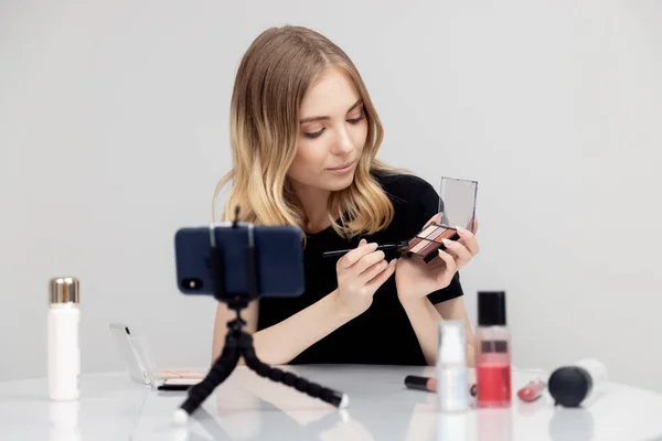 Belleza blogger joven mujer graba video tutorial por supuesto en maquillaje para la piel en el teléfono —  Fotos de Stock