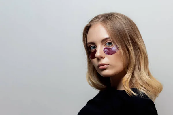 Retrato mujer joven feliz freelancer con parches para el cuidado de la piel ojeras oscuras bajo los ojos. Concepto crema hidratante tratamiento cara —  Fotos de Stock