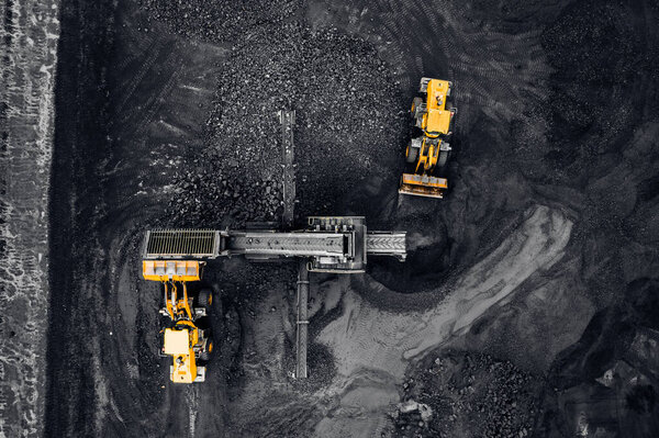 Aerial top view open mine, Yellow Excavator loads anthracite for crushing into coal crusher
