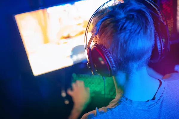 Joven deportista cibernético en auriculares mira en la pantalla blanca de la computadora en línea corriente, copia de la maqueta de espacio para los esports de torneos —  Fotos de Stock