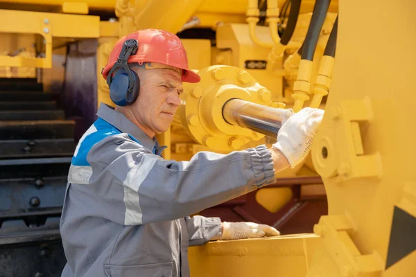 Mecánico profesional comprueba el equipo del sistema de manguera hidráulica en la excavadora para elevar el cubo — Foto de Stock