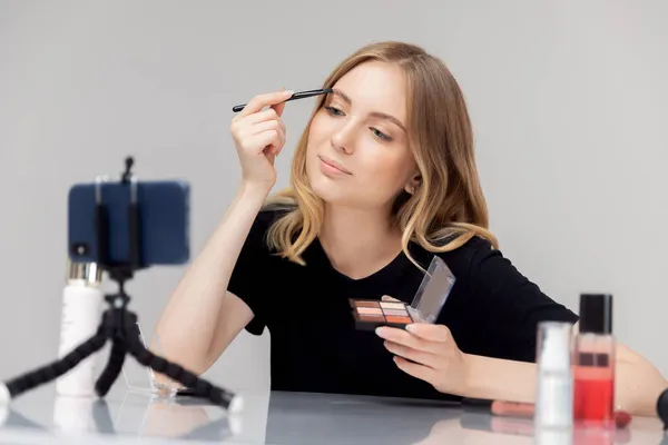 Influencer blogger belleza mujer joven graba video tutorial por supuesto en la piel facial y el cuidado de las cejas en el teléfono —  Fotos de Stock