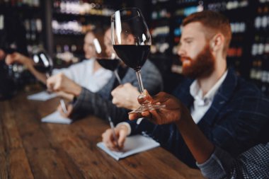 Kırmızı şarap içen adam ve kadın degustation not defterine not alıyor.