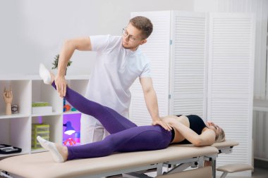 Osteopat terapist antremandan sonra bacak kaslarıyla çalışıyor. Sporcu kadınlar için konsept spor masajı