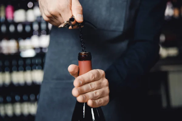 Sommelier abre cortiça de garrafa de vinho tinto com saca-rolhas — Fotografia de Stock