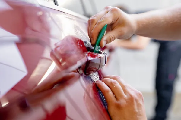 Installazione master close-up in zona a rischio sotto maniglie auto rossa. La protezione della vernice è un film in vinile — Foto Stock