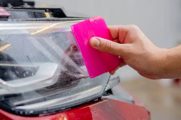 Proceso de primer plano proteger película de vinilo para gafas faros coche rojo moderno —  Fotos de Stock