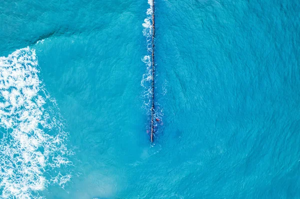 Vista aérea de rompeolas con olas de mar, agua azul limpia alrededor de la playa — Foto de Stock
