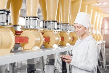 Arkaplan tahıl teçhizatında kadın operatör. Buğday unu üretmek için modern elektrik değirmeni makineleri