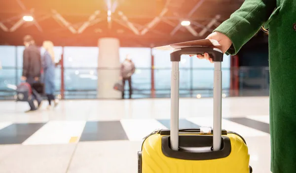 Konzeptbanner Flugreisende Frau in grünem Mantel hält Reisepass mit Ticket und gelben Koffer am Flughafen — Stockfoto