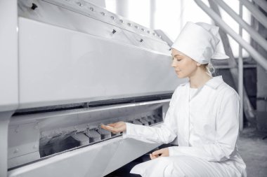 Buğday unu üretmek için modern elektrikli değirmen makineleri. Kadın operatör bitmiş gıda ürünlerinin kalitesini kontrol ediyor