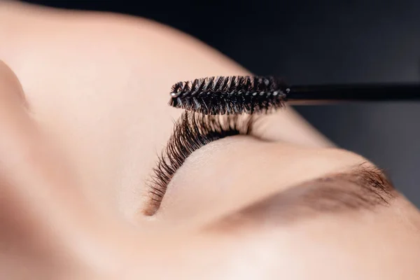 Procedimiento de extensión de pestañas con peine. Negro falso largo pestañas hermosa mujer ojos — Foto de Stock