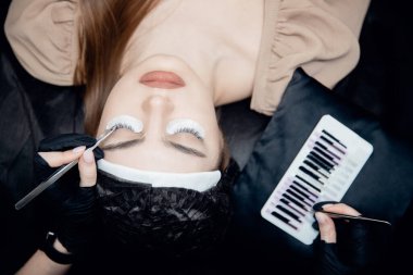 Kirpik uzatma prosedürü üst görünüm. Üstad cımbız sahte 2D kirpikleri güzel bayan gözleri