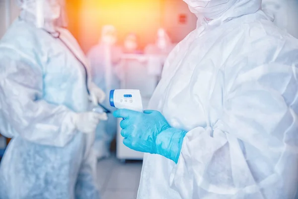 Clínica da equipe de enfermagem com termômetro verificar o paciente de saúde em trajes de proteção e máscaras na área vermelha de controle covid19 coronavirus banner — Fotografia de Stock