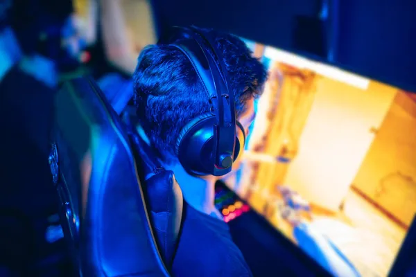 Θολή φόντο επαγγελματίας παίκτης που παίζει τουρνουά σε απευθείας σύνδεση παιχνίδια υπολογιστή με ακουστικά, κόκκινο και μπλε — Φωτογραφία Αρχείου