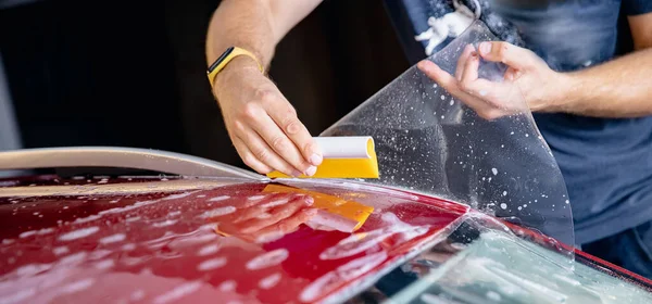 Master man instala tira de película de vinilo en zona de riesgo de parabrisas para proteger la pintura de la carrocería del coche de arañazos y virutas —  Fotos de Stock